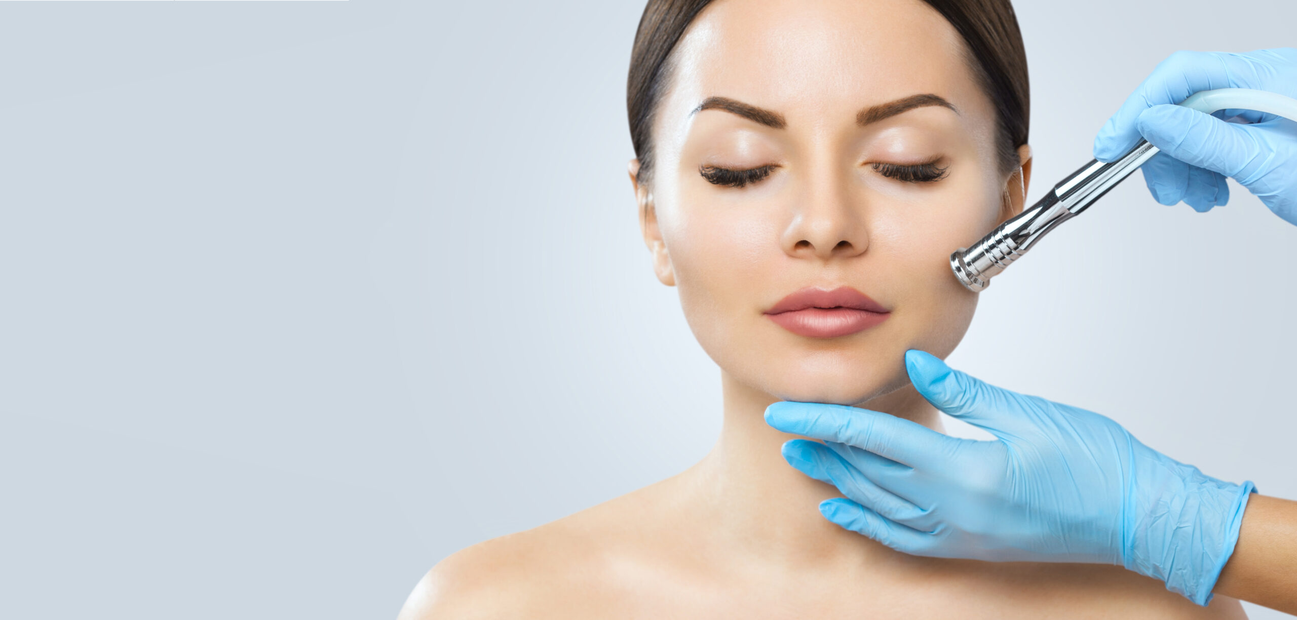 The cosmetologist makes the procedure Microdermabrasion of the face skin of a beautiful woman in a beauty salon.Cosmetology and professional skin care.